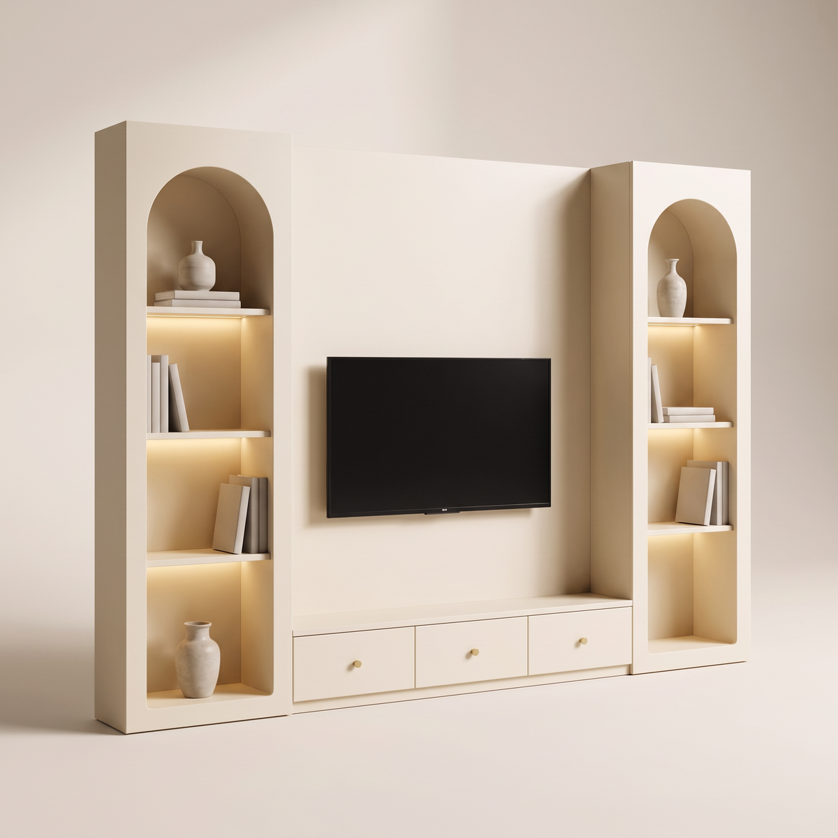Archway Media Wall in matte warm ivory with two arched LED-lit display niches and a three-drawer console with brass knobs below the TV, three-quarter view