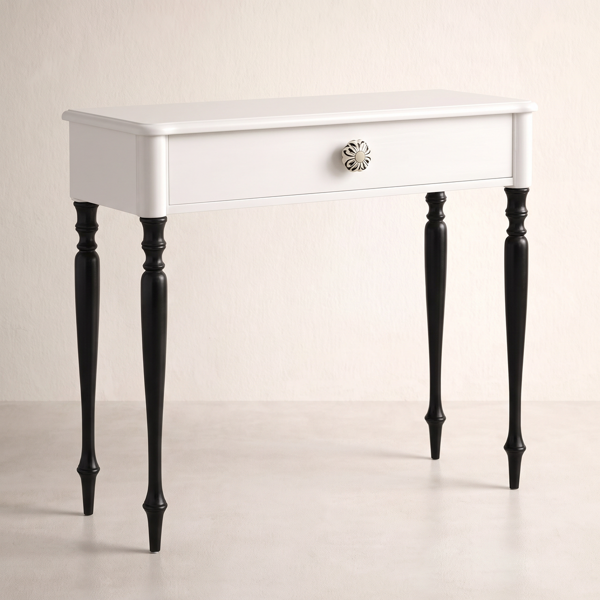 Belle console table in white with one drawer, floral ceramic knob and black turned legs, front three-quarter view