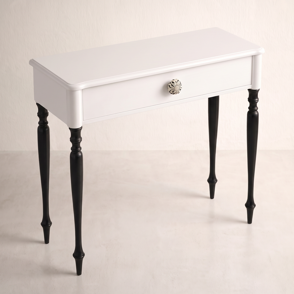 Belle console table in white with floral ceramic knob and black turned legs, elevated three-quarter view showing the top