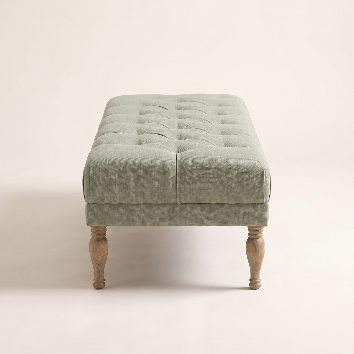 Belmont Sage ottoman bench, end view showing the tufted top and turned legs