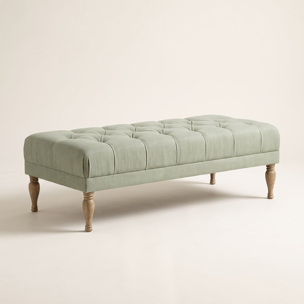 Belmont Sage ottoman bench in sage-green fabric with button-tufted top and turned wooden legs, front three-quarter view