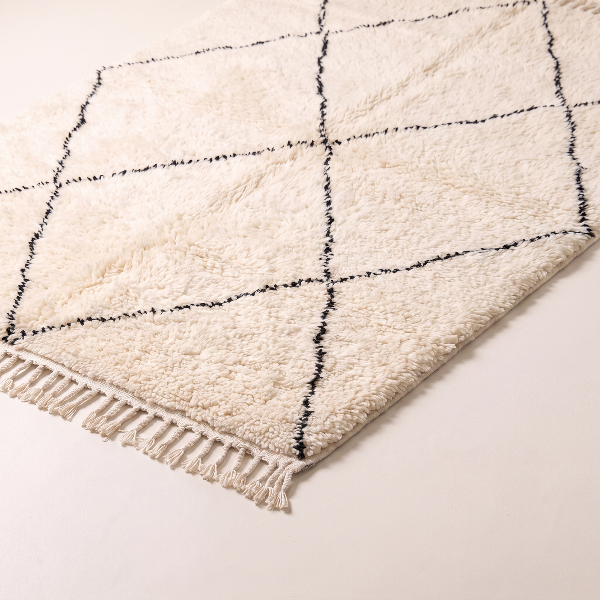 Berber Cloud Shag corner close-up showing deep ivory wool pile, charcoal line and knotted fringe