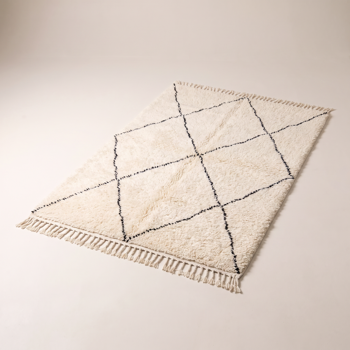 Berber Cloud Shag, long-pile ivory wool rug with charcoal hand-drawn diamond lattice and knotted fringes, elevated three-quarter view