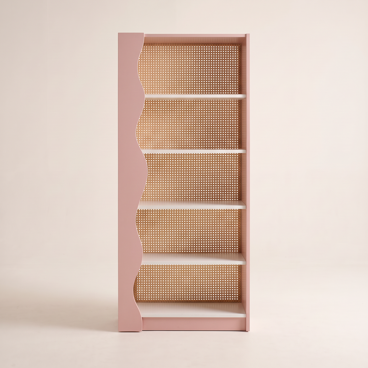 Blush Cane bookcase in blush pink with wavy side, white shelves and woven cane back, front view