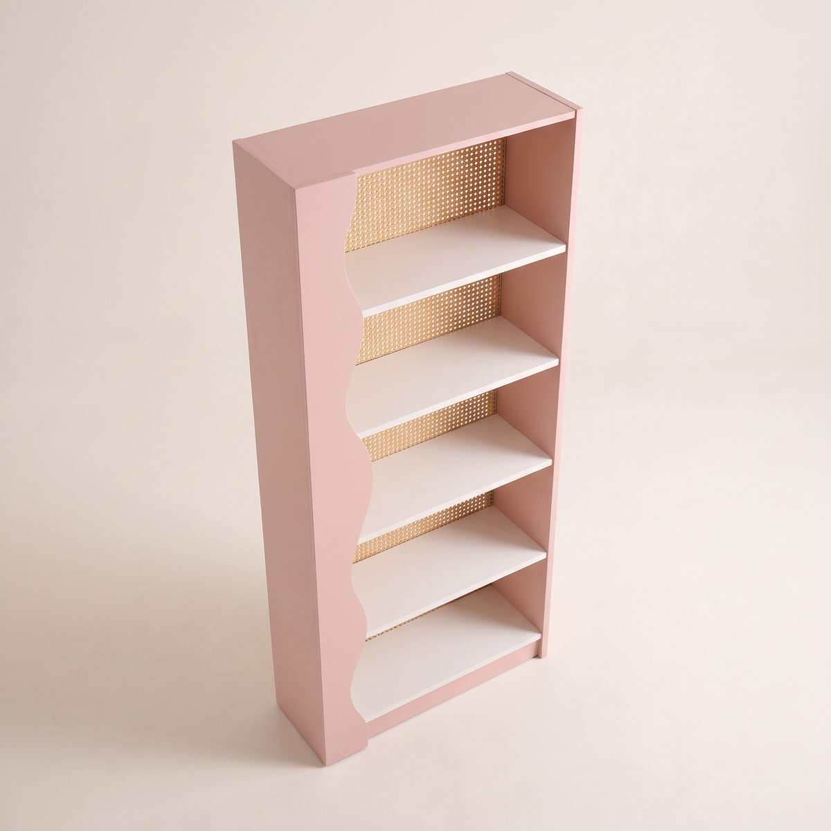 Blush Cane bookcase in blush pink with wavy side and woven cane back, elevated three-quarter view showing the top