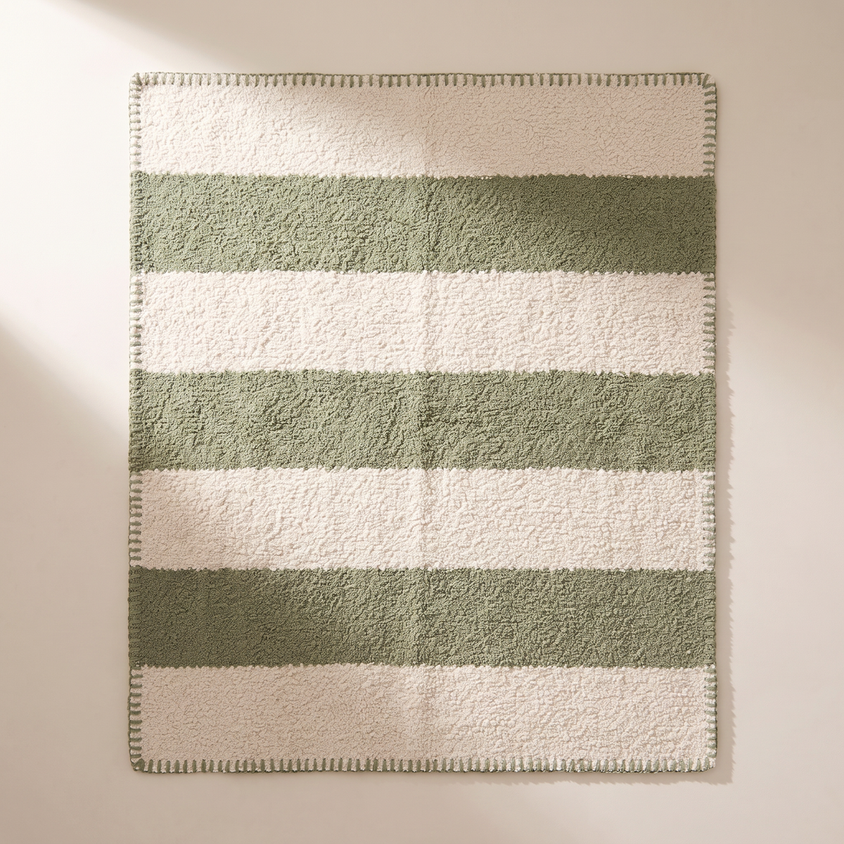 Bouclé Stripe Throw spread flat, overhead view of the alternating ivory and sage bands and whipstitched edges