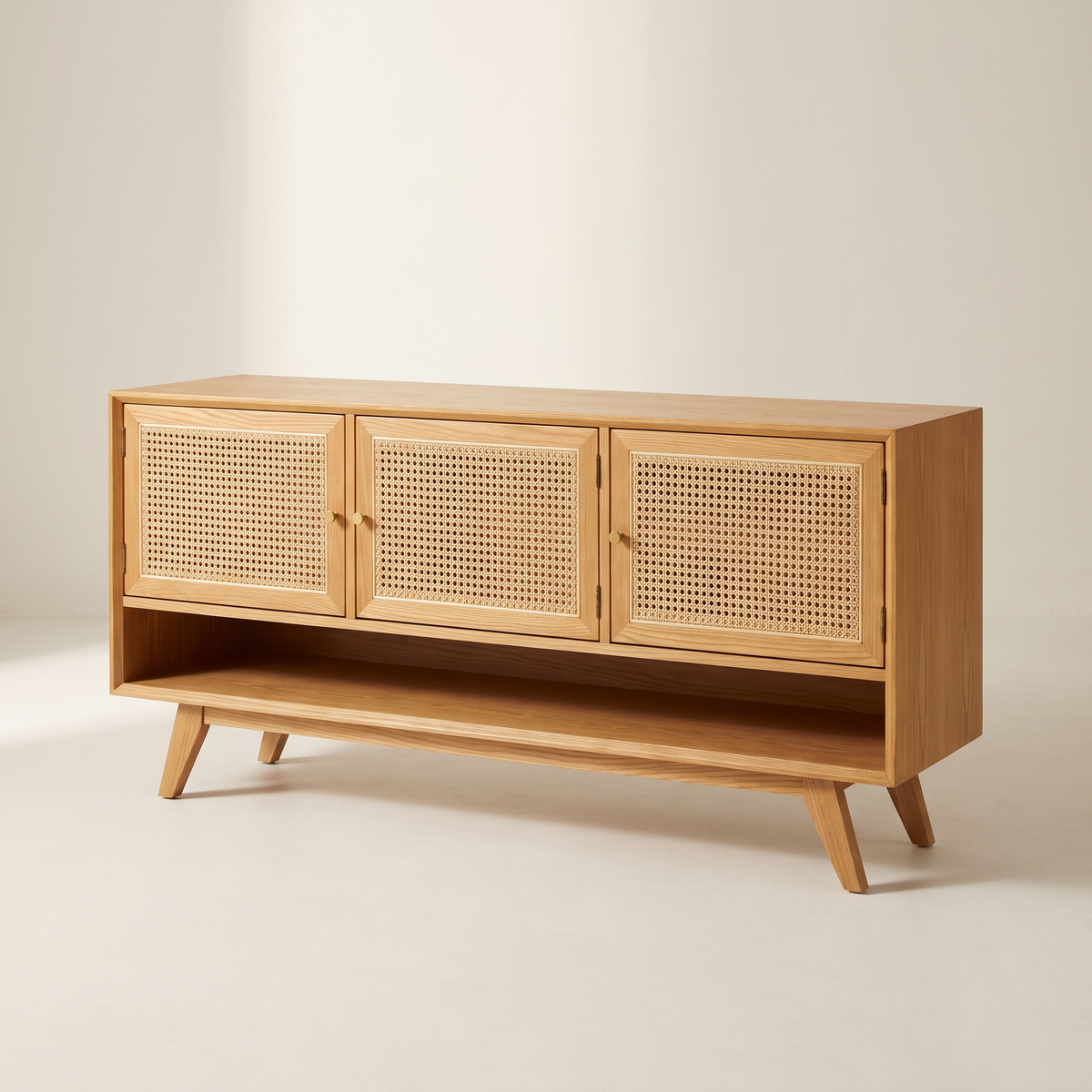 Cane Tempo TV unit in honey ash with three woven cane doors, brass knobs, open shelf and splayed tapered legs, three-quarter view