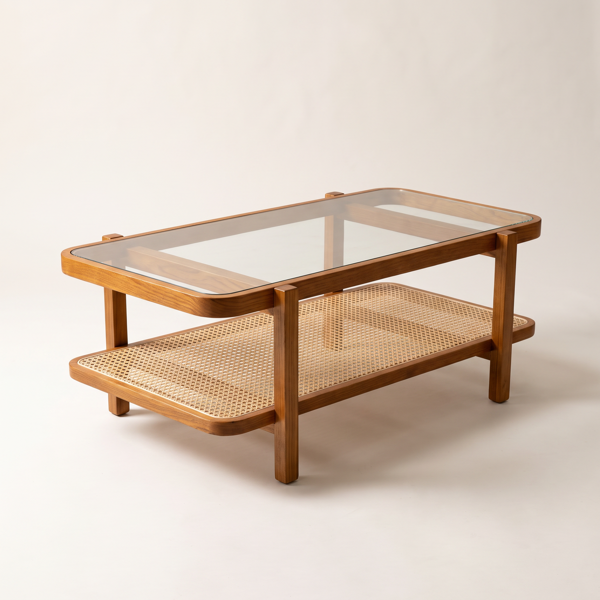 Canehaven coffee table in honey ash wood with clear glass top and woven cane shelf, front three-quarter view