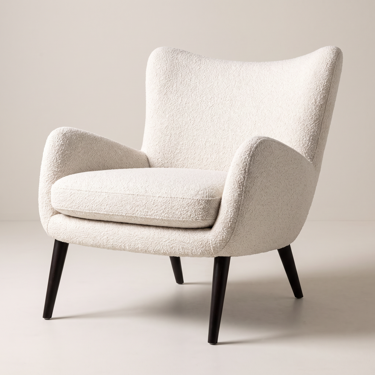 Canvas Ivory lounge chair in ivory bouclé upholstery with dark tapered wood legs, front three-quarter view