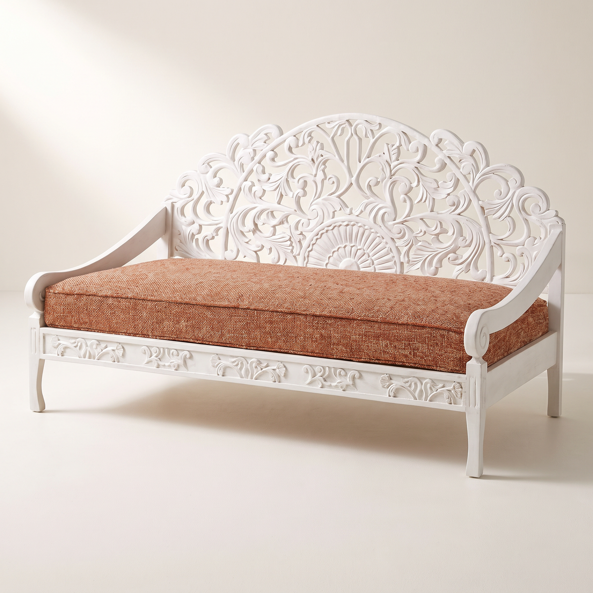 Carve White hand-carved white wooden sofa with openwork arched back and rust tweed seat cushion, front three-quarter view
