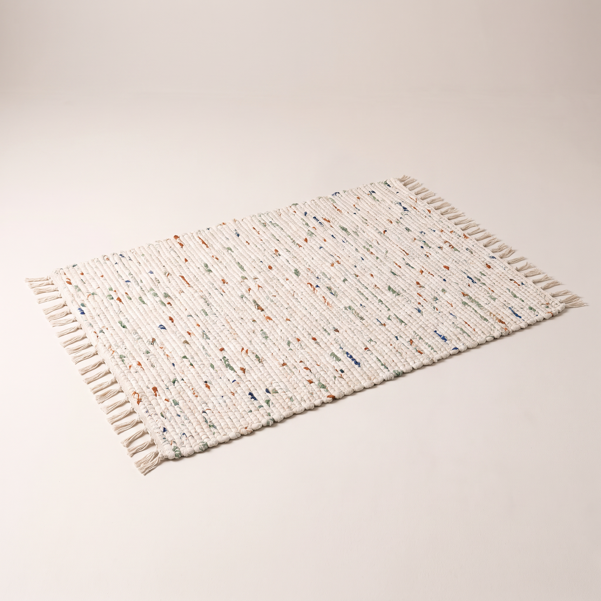 Chindi Rag Rug, flatwoven recycled cotton rag rug in ivory with sage, rust and indigo flecks, elevated three-quarter view