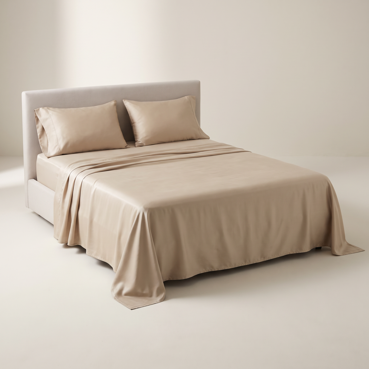 Cool Tencel Sheet Set in smooth sand-beige lyocell with a soft sheen and fluid drape, on a low studio bed, front three-quarter view