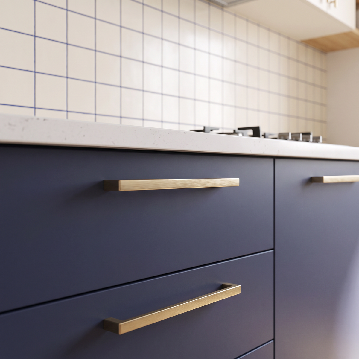 Dhoop Two-Tone detail of indigo matte drawers with brushed brass bar pulls below ivory tiles with indigo grout