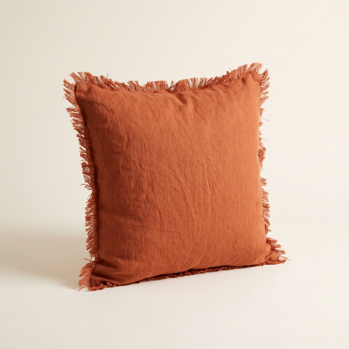 Fringe Linen Cushion in washed rust linen with frayed self-fringe edges, front three-quarter view
