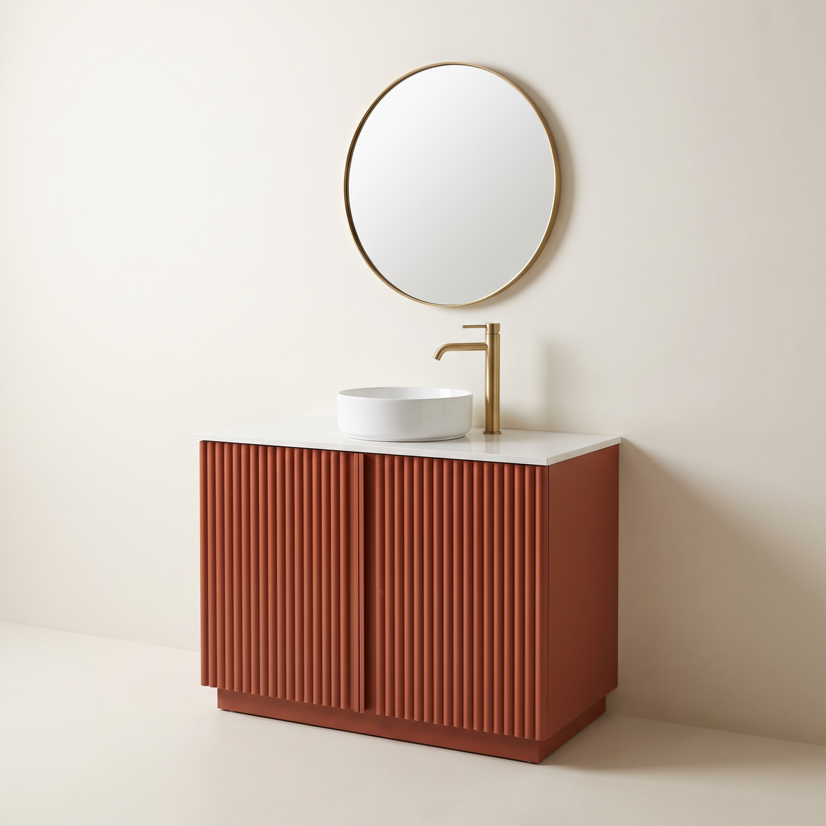 Furrow Rust Vanity with fluted rust-terracotta doors, recessed plinth, white quartz top, round white vessel basin, brass tap and round brass-framed mirror, three-quarter studio view