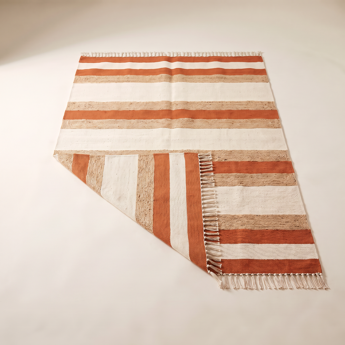 Ganga Stripe Dhurrie with a corner folded back showing the reversible weave and fringe