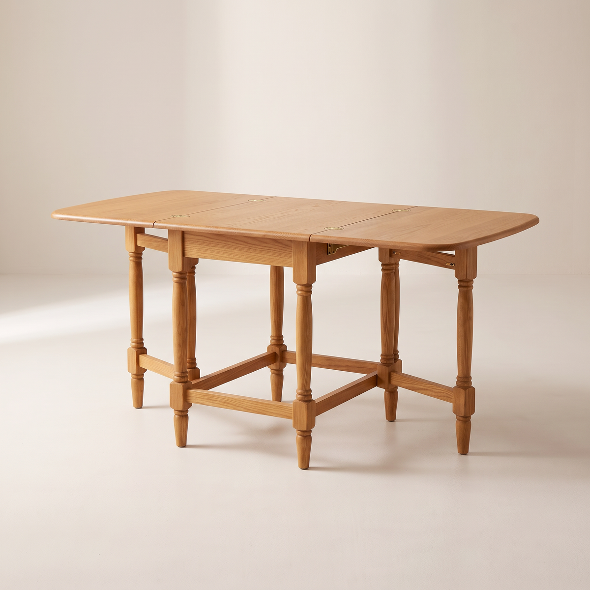 Gateleg Compact drop-leaf table in honey solid ash, both leaves raised on turned gate legs with ring details, front three-quarter view