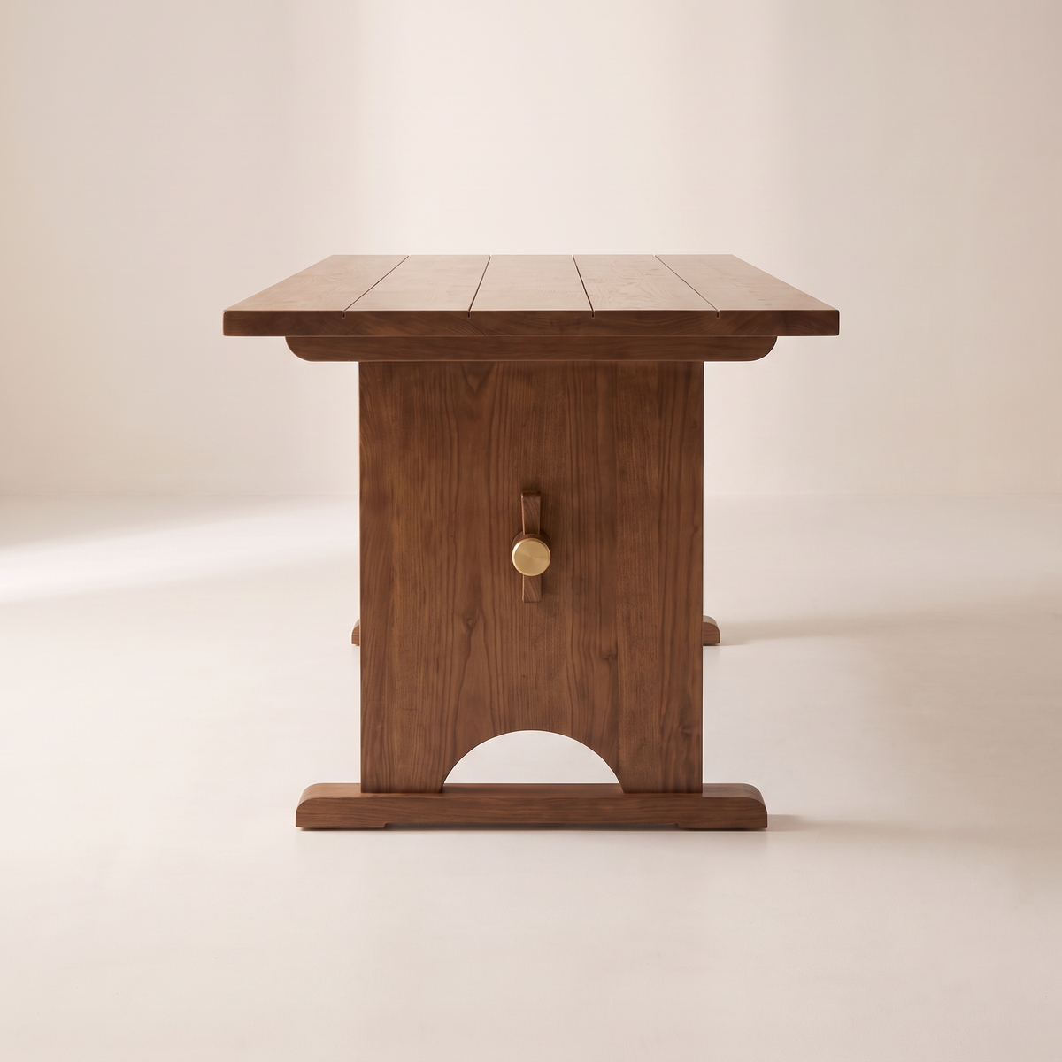 Haveli Trestle dining table end view showing the arched trestle panel and brass-capped wedge peg