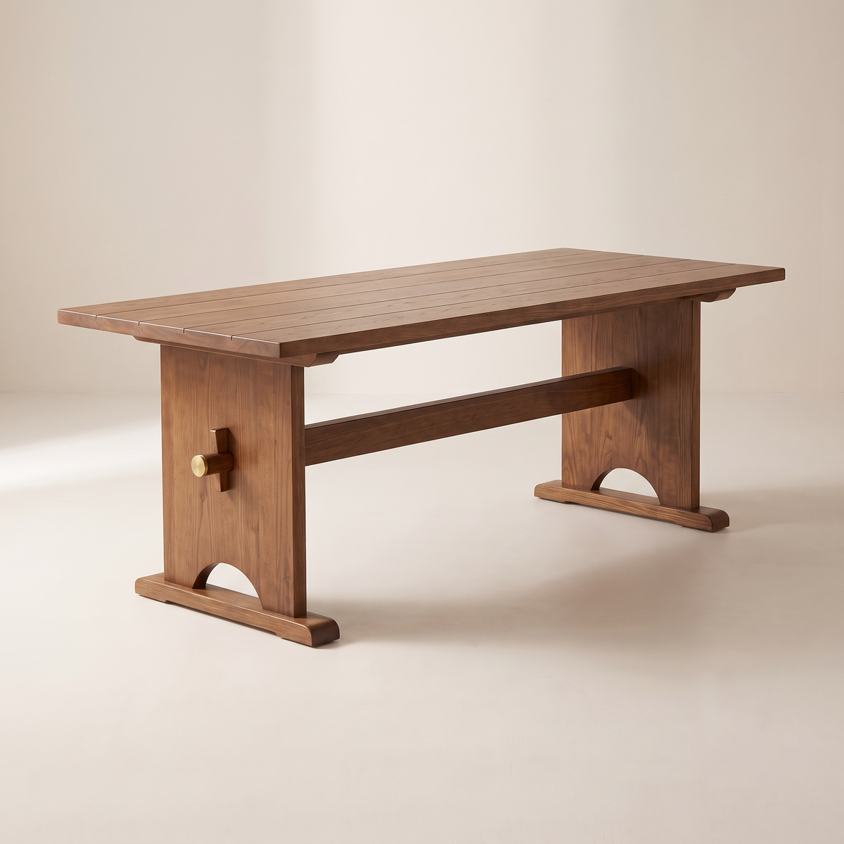 Haveli Trestle dining table in walnut-honey solid ash with board-joined top, arched end trestles and brass-capped wedge pegs, front three-quarter view