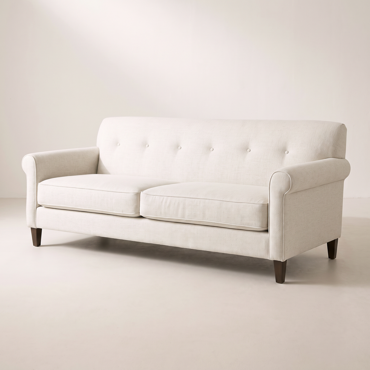 Haven Ivory sofa in ivory woven upholstery with button-tufted back, rolled arms and dark tapered wood legs, three-quarter view