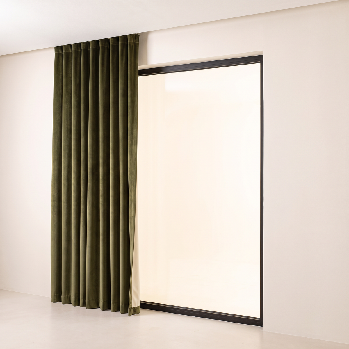 Hush Velvet Blackout olive velvet curtains stacked open to one side of a tall window