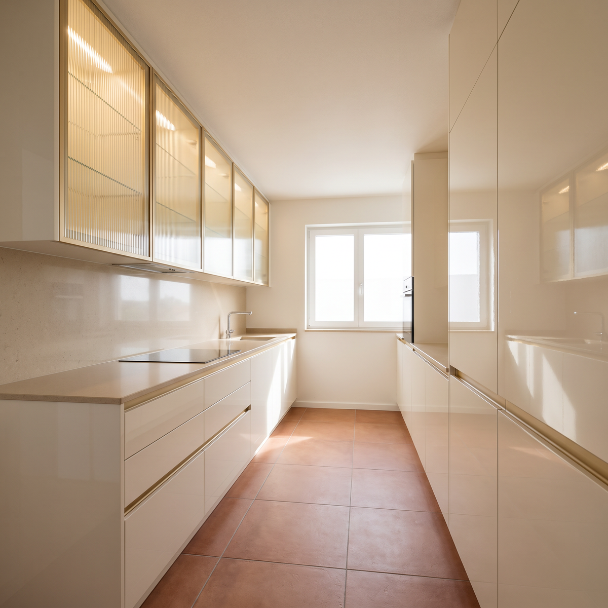 Juniper Galley modular kitchen with ivory high-gloss fronts, champagne-gold finger pulls and fluted glass wall cabinets, view down the galley