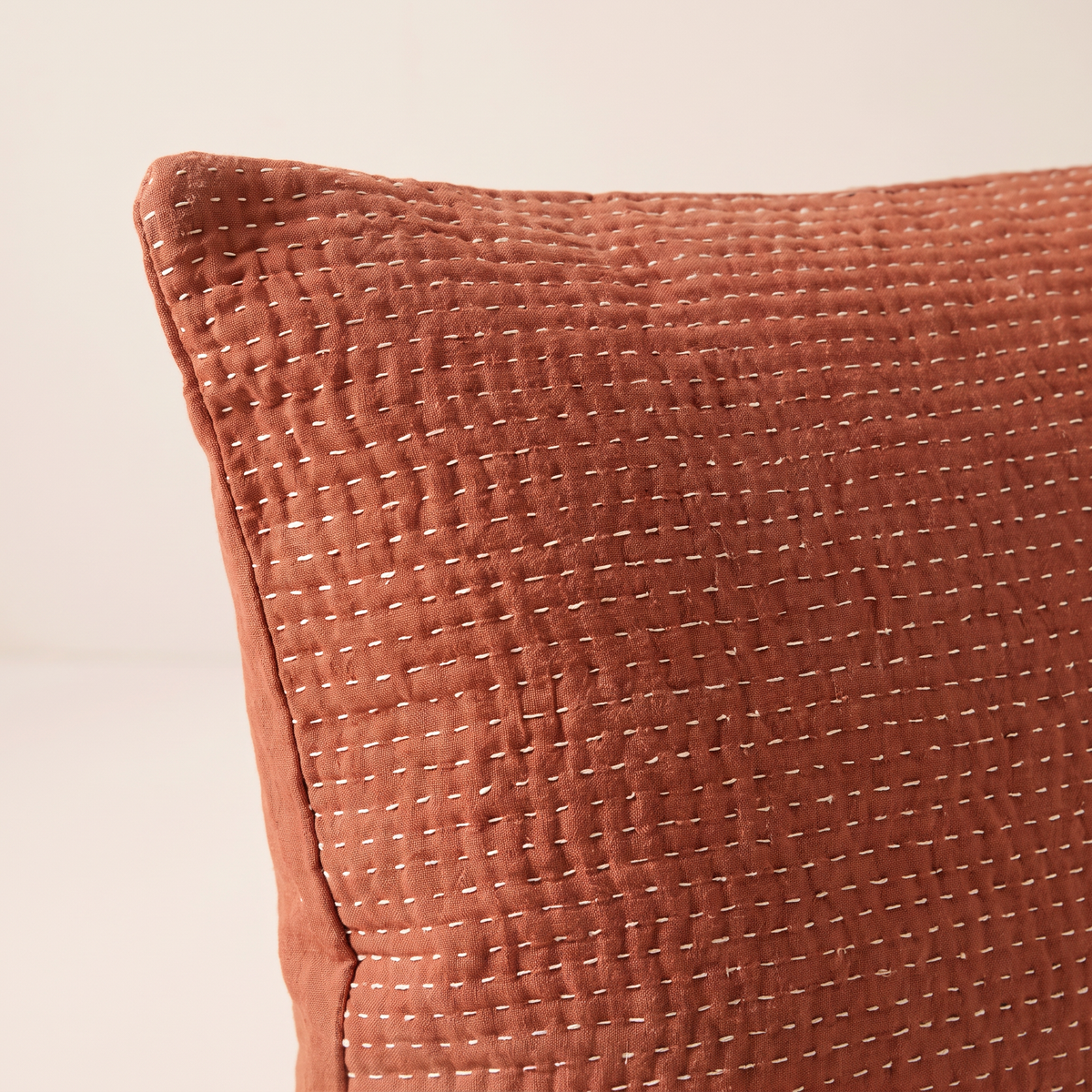 Close-up of Kantha Lumbar showing hand running stitches and crinkled rust cotton