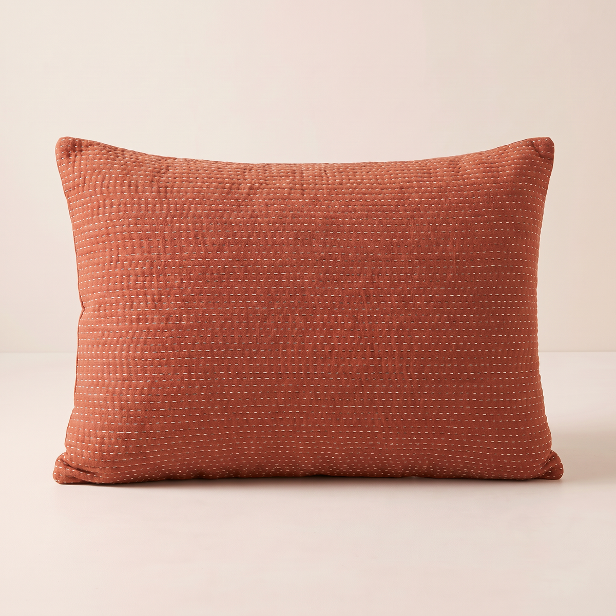 Kantha Lumbar cushion in rust cotton with cream running stitch, straight front view
