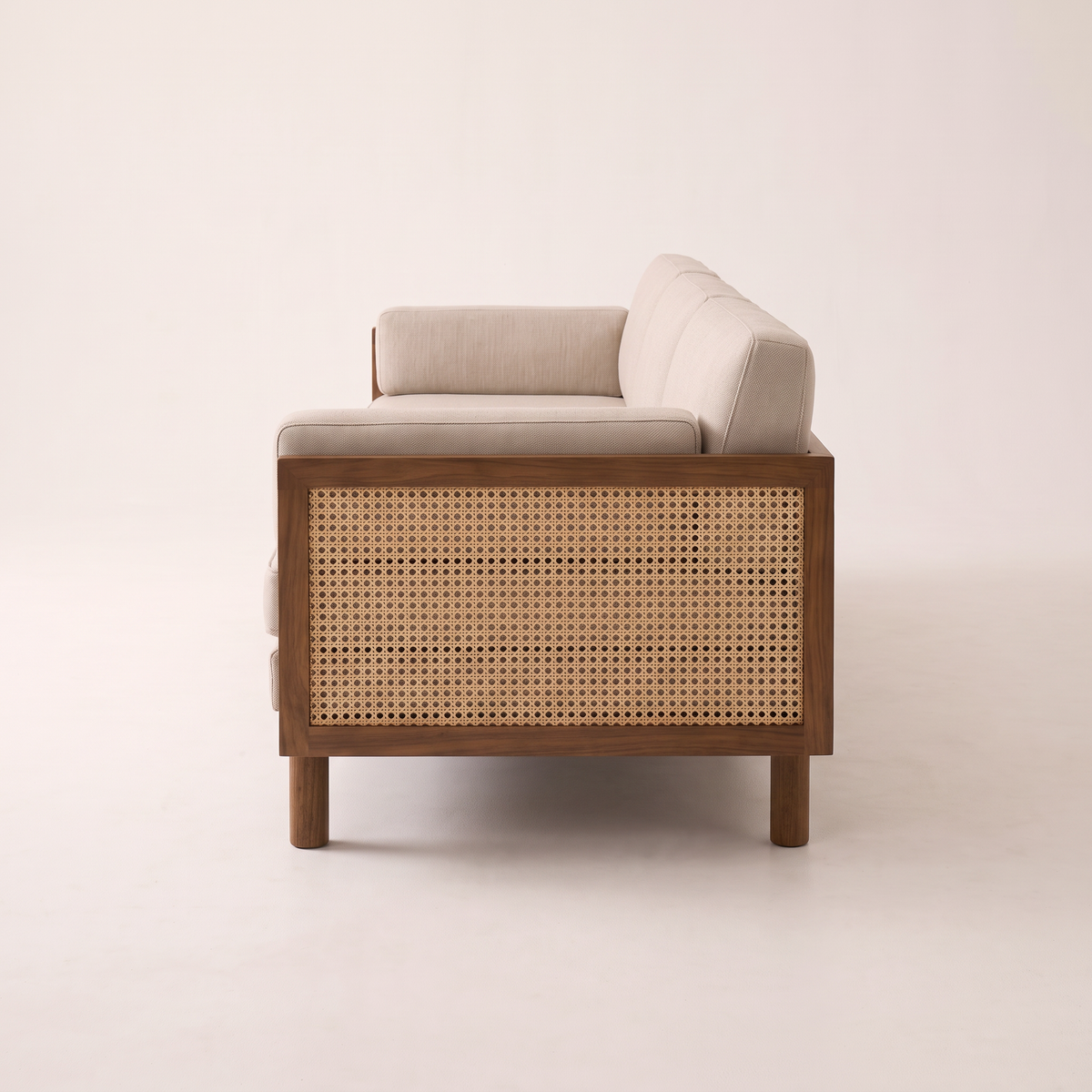 Kora Cane sofa with wooden frame, cane arm panels and oatmeal upholstery, side profile view
