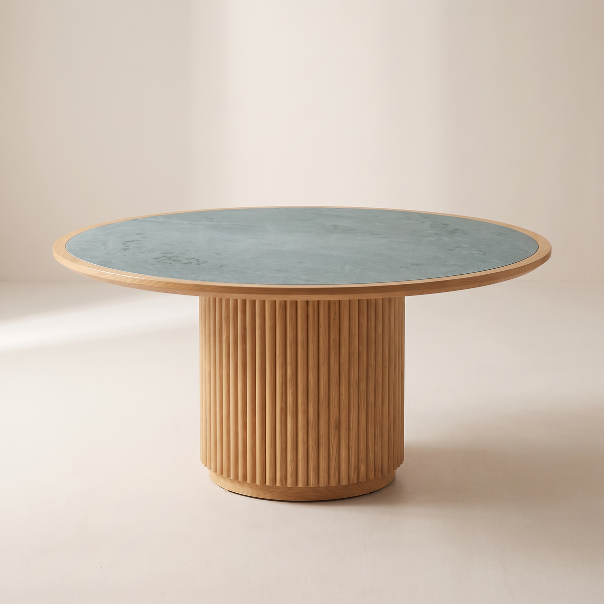 Kota Round dining table with honed blue-grey-green Kota stone top, thin honey ash rim and fluted ash drum base, front three-quarter view