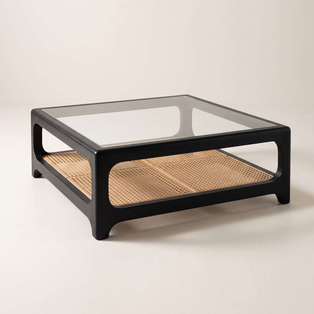 Linea Cane Black coffee table with black ash frame, clear glass top and natural cane shelf, front three-quarter view
