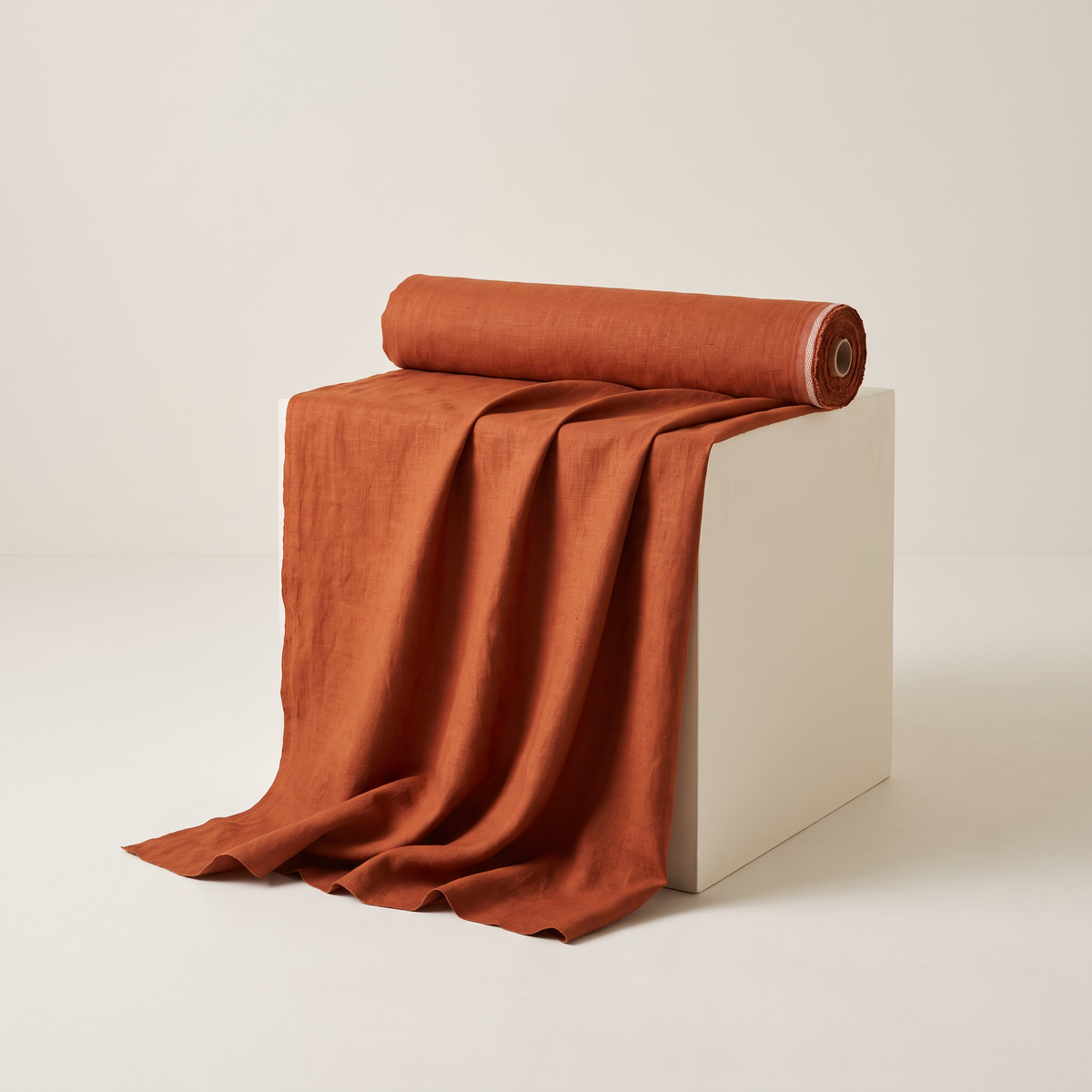 Linen Rust upholstery fabric, rust-orange slubbed linen-cotton, unrolled from a bolt and draped over a studio plinth