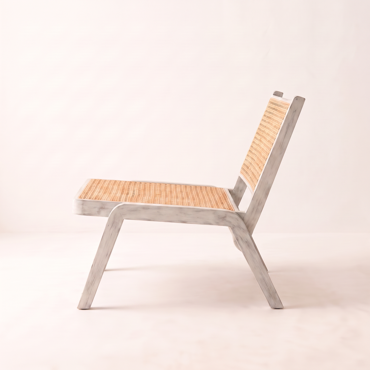 Loom White lounge chair, side profile showing the splayed whitewashed legs and reclined cane back