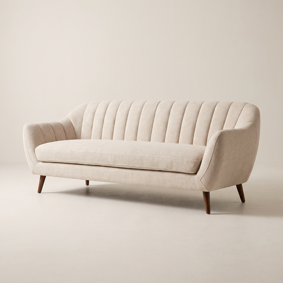 Luna Ivory sofa in ivory channel-tufted upholstery with dark tapered wooden legs, front three-quarter view