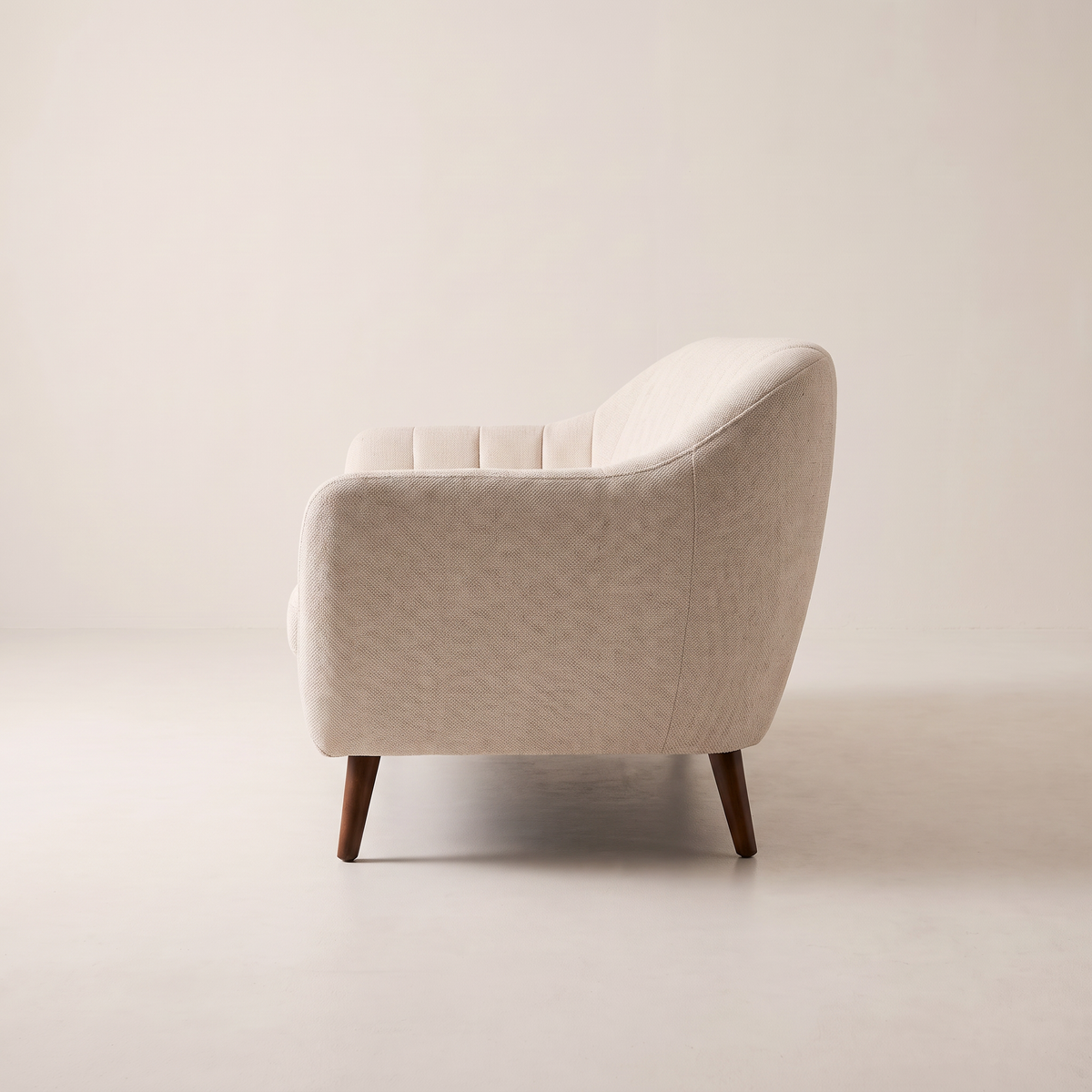 Luna Ivory sofa in ivory channel-tufted upholstery with dark tapered wooden legs, side profile view