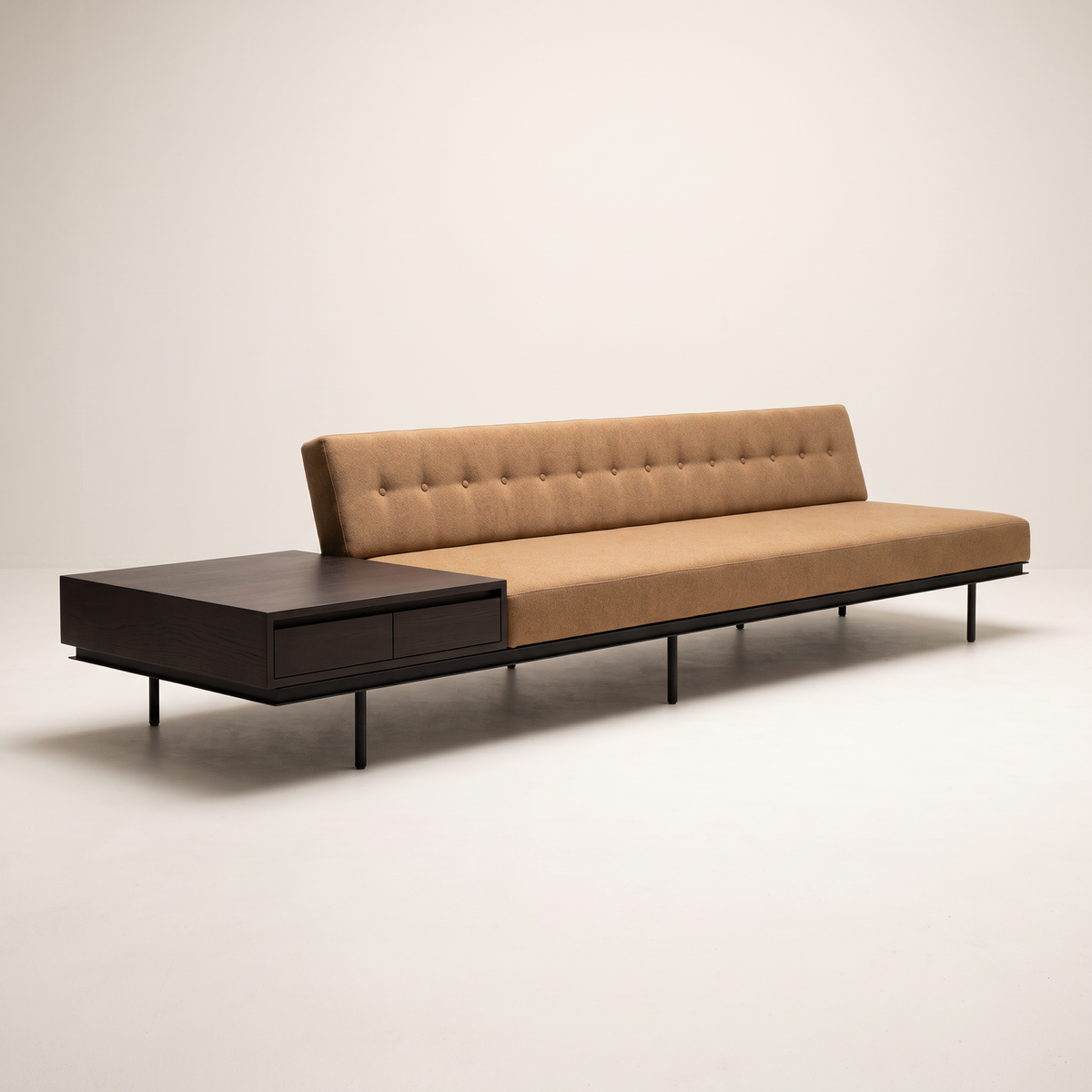 Monolith Brown armless sofa in camel-tan upholstery with integrated dark wood drawer table and black metal legs, three-quarter view