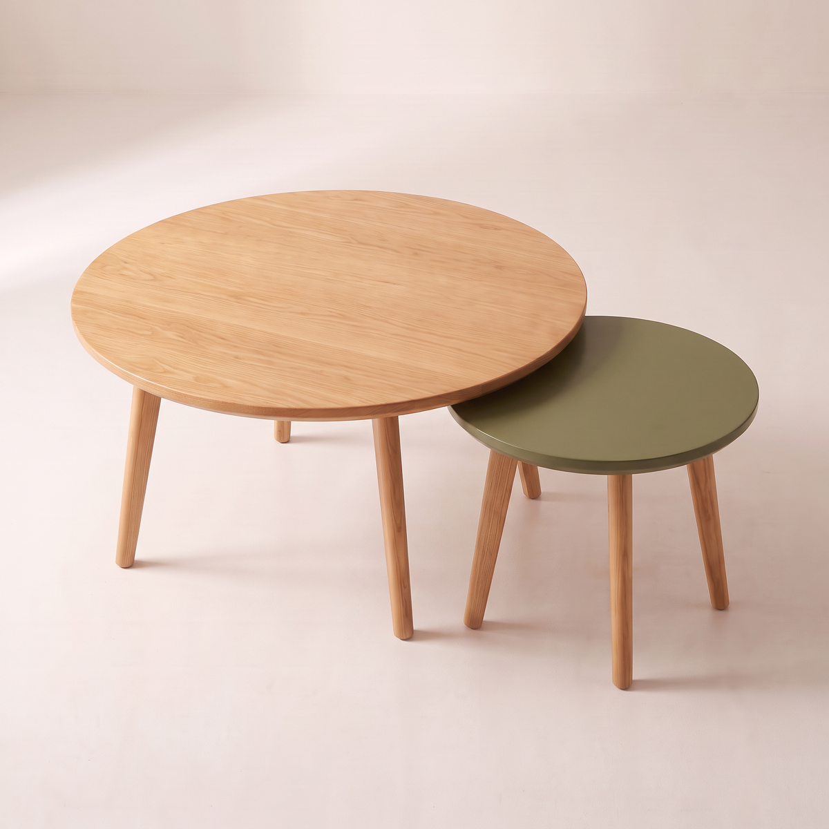 Orbit Nest nesting coffee tables seen from above, olive top sliding under the honey ash top, elevated view