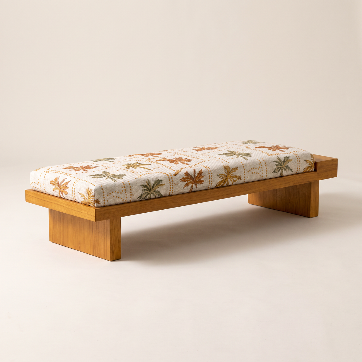 Palmira 1 low wooden platform bench with cream palm-print cushion, front three-quarter view