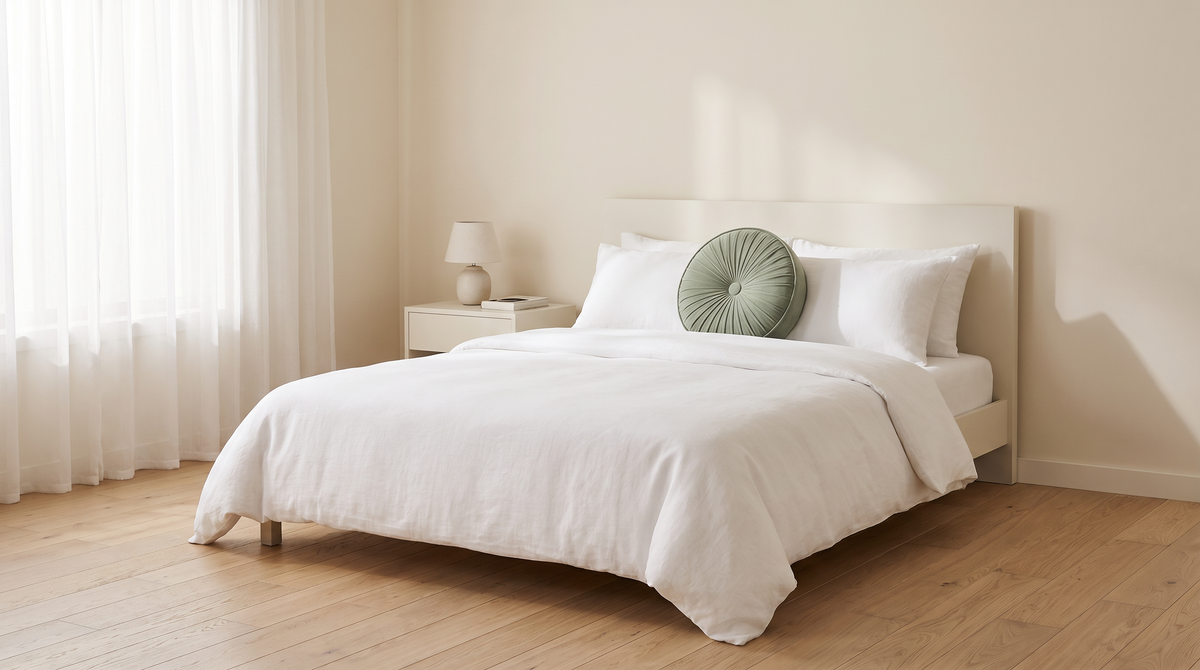 Pinwheel Round Cushion styled in front of white pillows on a bed in a calm bedroom