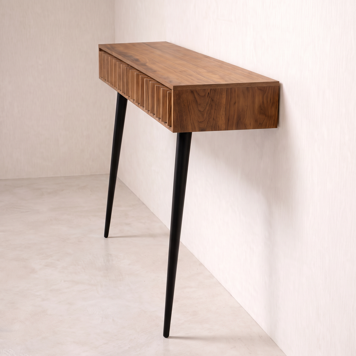 Pleat wall console in wood veneer with black tapered legs, end view against the wall