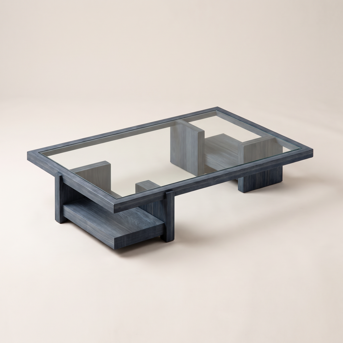 Plinth Blue coffee table with glass top in slate blue-grey wood frame on block plinth bases, front three-quarter view
