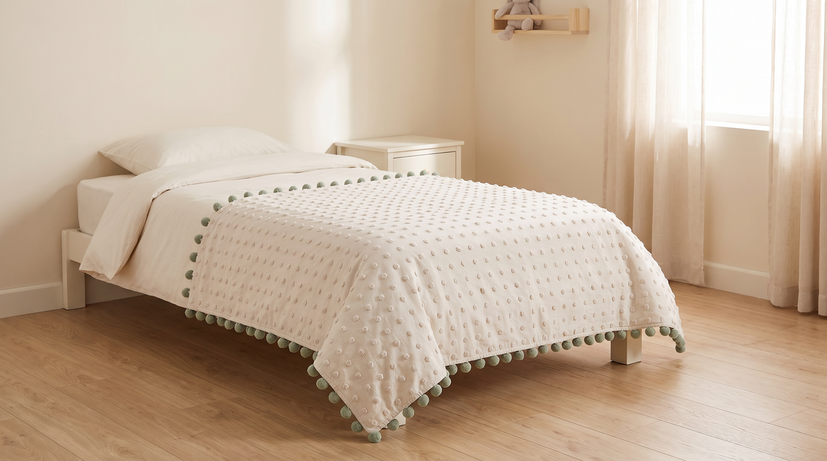 Pom-Pom Tufted Throw spread across a single bed in a calm children's room