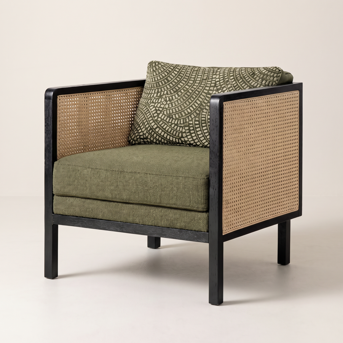 Raffia Black lounge chair with black wood frame, natural cane arms and back and olive-green cushions, front three-quarter view