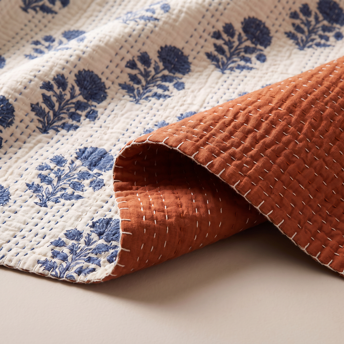 Reversible Kantha Throw close-up of kantha running stitches, indigo floral print and rust reverse