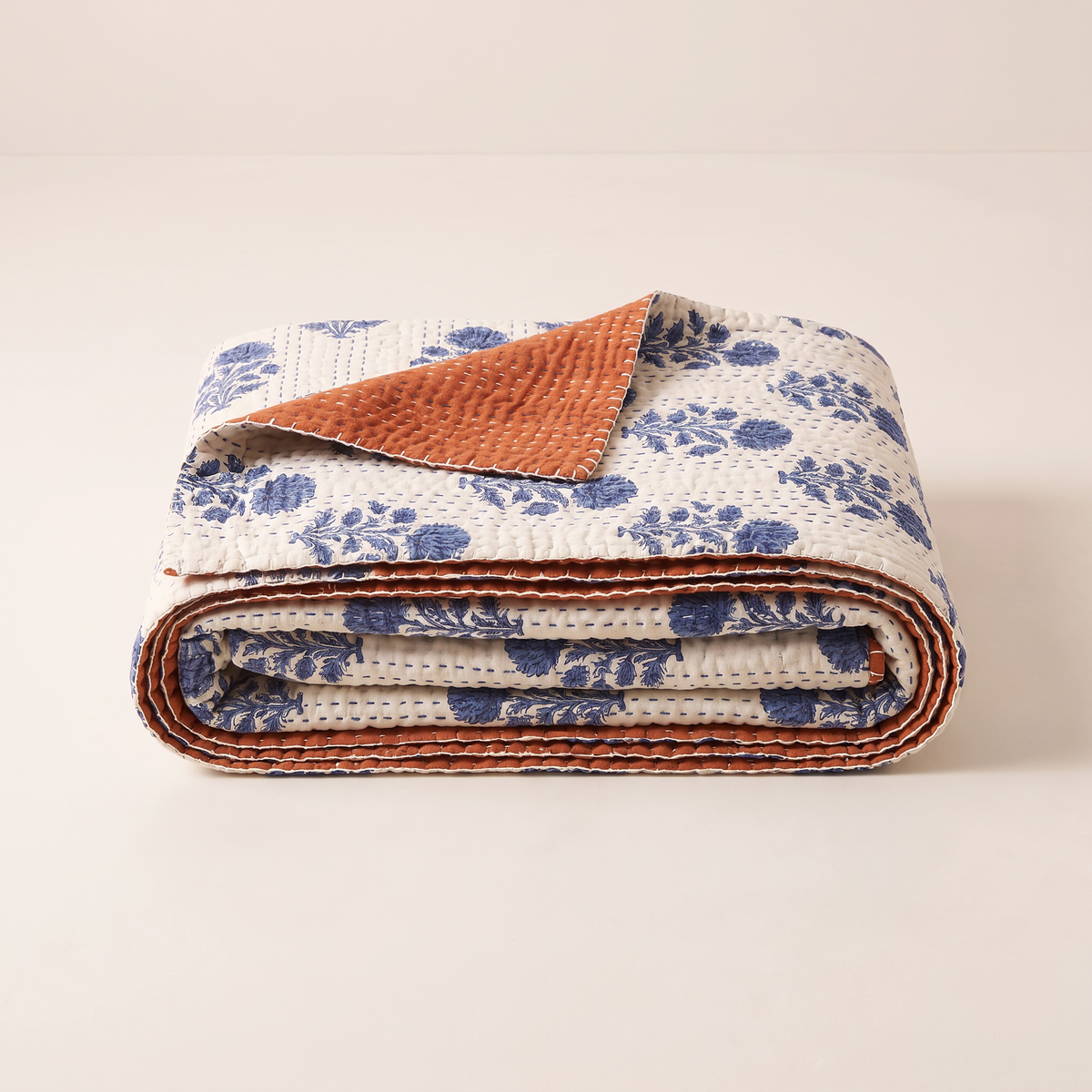 Reversible Kantha Throw folded with a corner turned back showing the indigo floral face and rust reverse