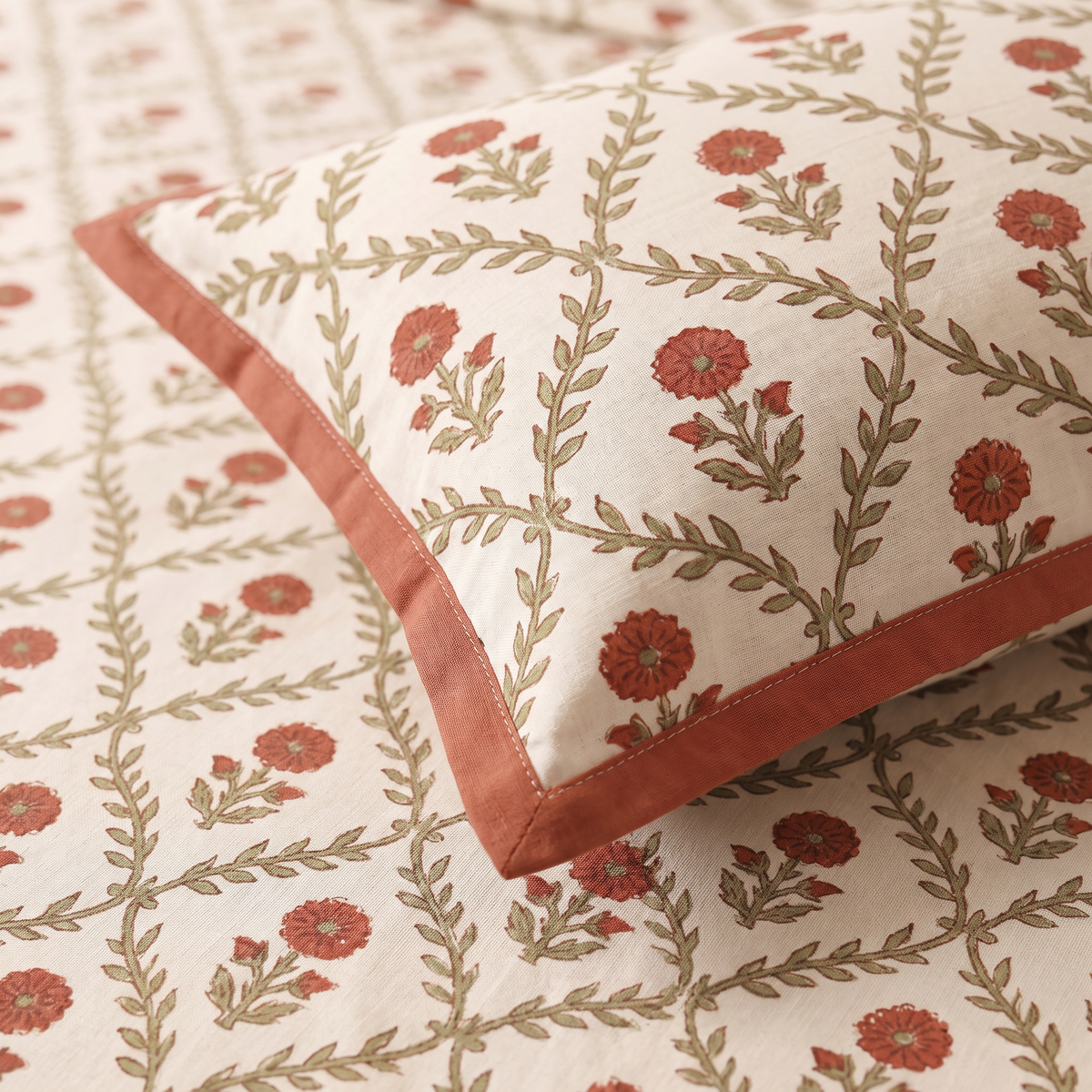 Close-up of Sanganer Block pillow cover with rust border on the hand block-printed floral jaal sheet