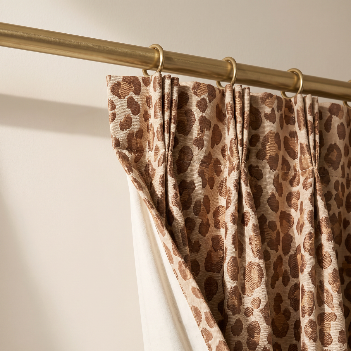 Close-up of Savanna Jacquard Drape pinch-pleat heading, brass rings, leopard jacquard weave and ivory cotton lining