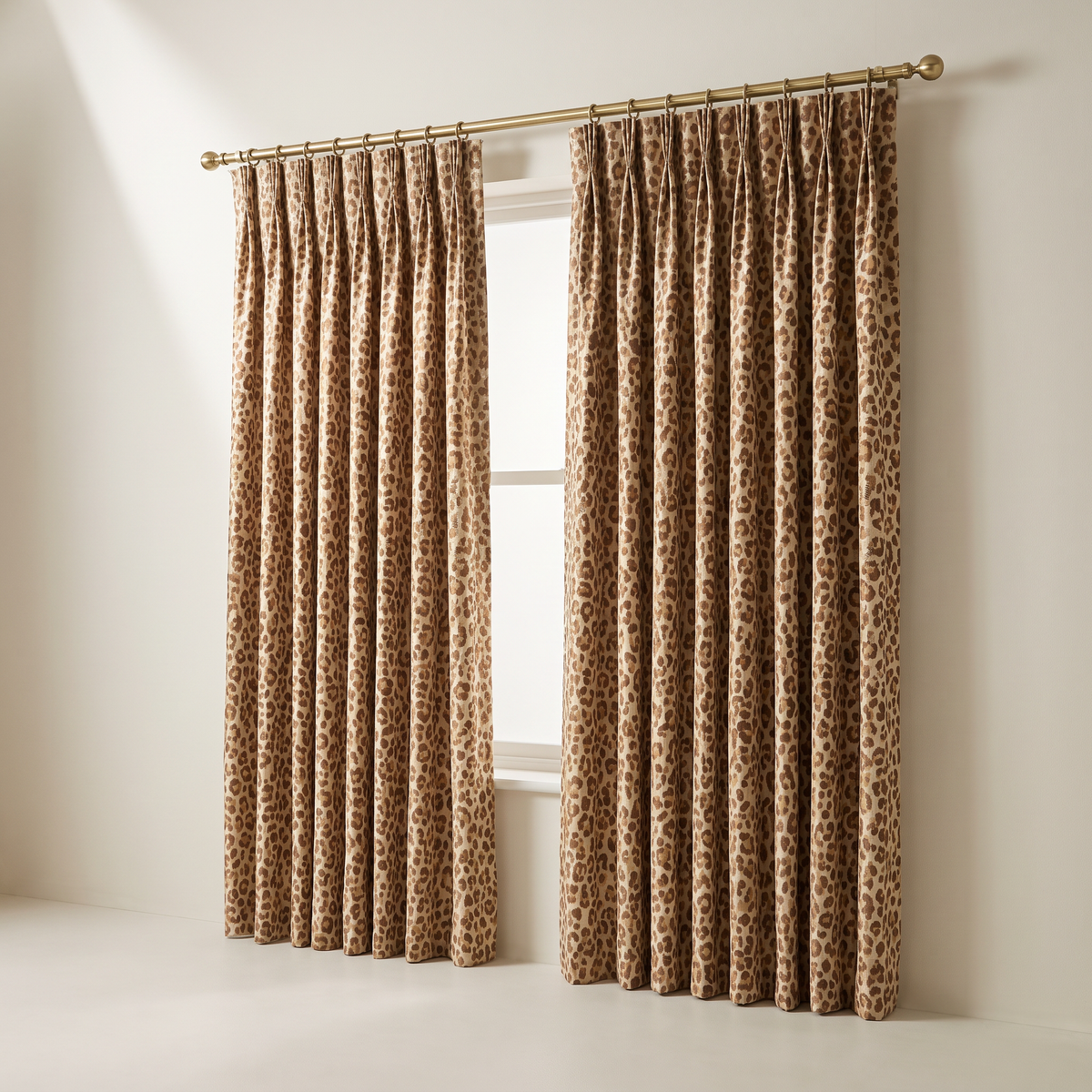 Savanna Jacquard Drape curtains in caramel and chocolate leopard jacquard on sand, pinch pleats on a brass rod, front three-quarter view