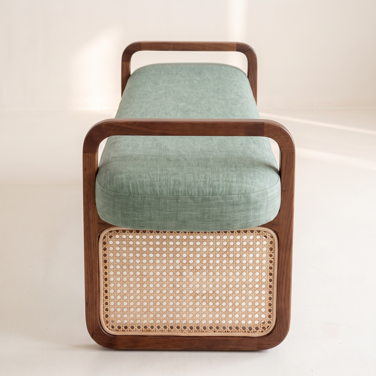 Serena Sage ottoman bench end view showing walnut loop frame and woven cane panel