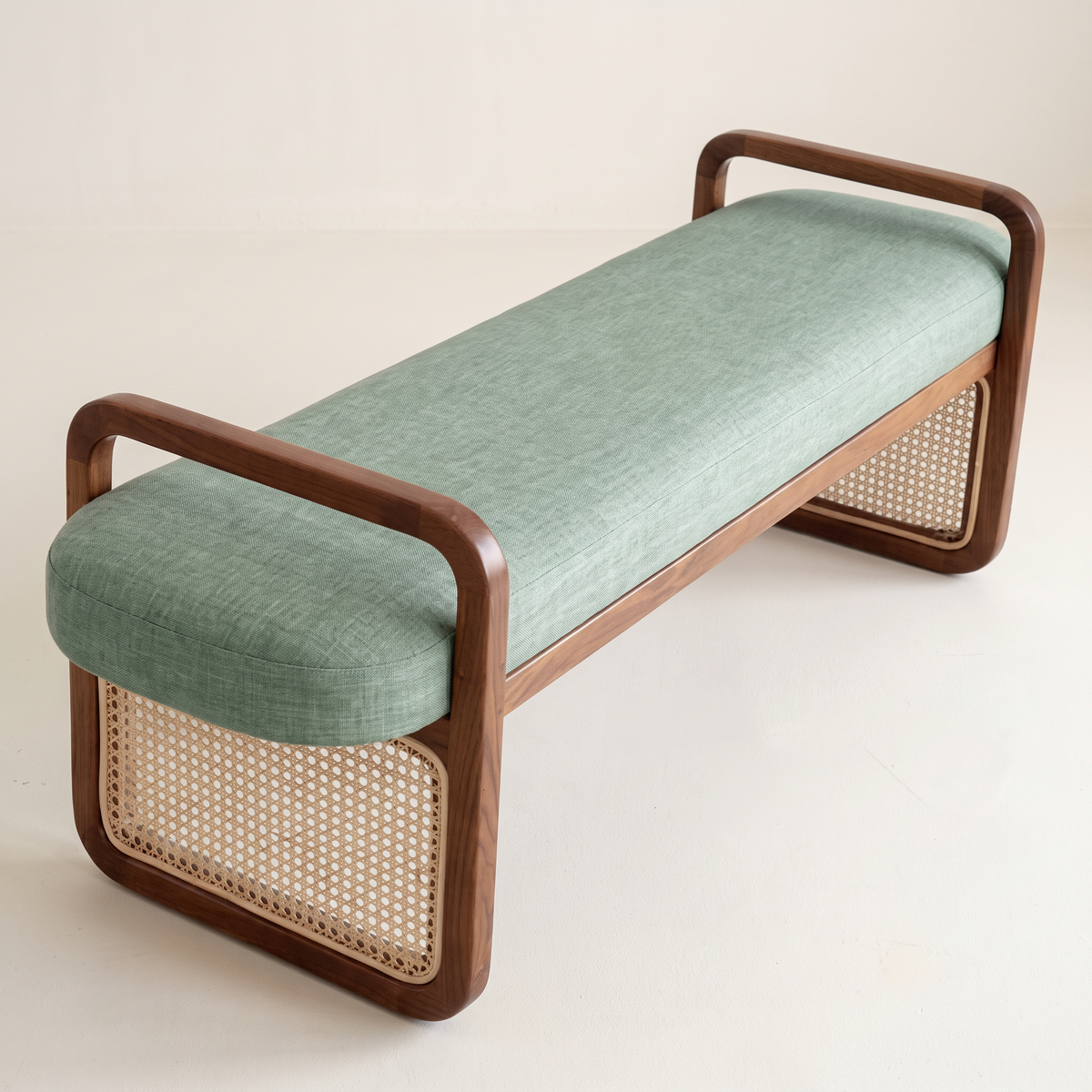 Serena Sage ottoman bench in sage green linen with walnut loop end frames and cane panels, front three-quarter view